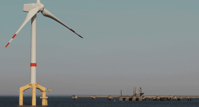 Floating offshore wind turbine operating near a coastal energy facility, supporting the expansion of renewable energy markets in 2025.
