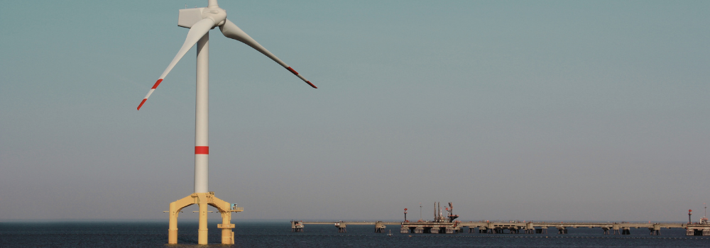 Floating offshore wind turbine operating near a coastal energy facility, supporting the expansion of renewable energy markets in 2025.