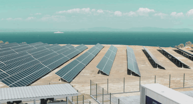 Solar panels and battery storage units overlooking the sea, supporting the transition to clean energy and helping to achieve net zero targets by 2050.