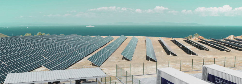 Solar panels and battery storage units overlooking the sea, supporting the transition to clean energy and helping to achieve net zero targets by 2050.