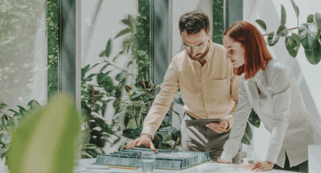 Navitas renewable energy specialists reviewing a sustainable solar project model in a green, eco-friendly office environment.