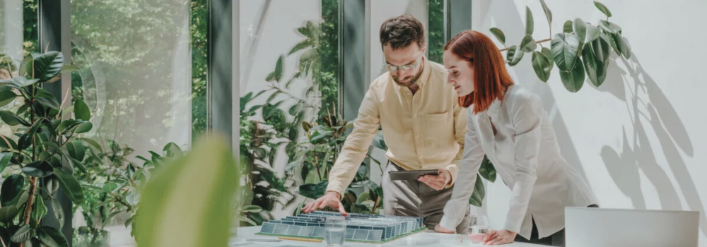 Navitas renewable energy specialists reviewing a sustainable solar project model in a green, eco-friendly office environment.