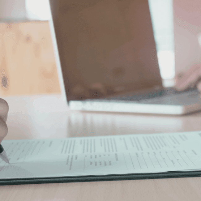 Renewable energy professional reviewing their CV on a laptop, with wind turbines in the background, representing career opportunities in the clean energy sector.