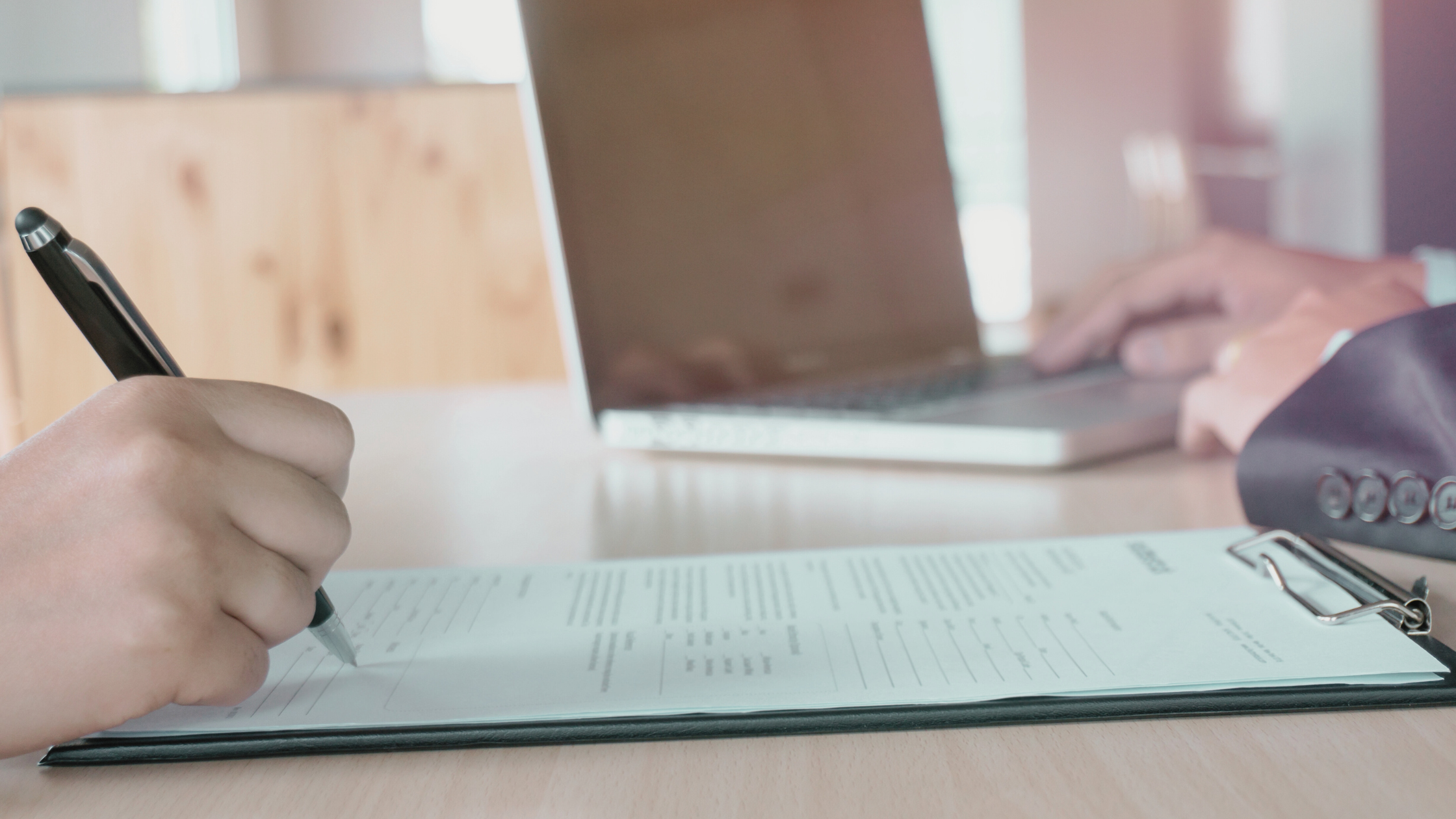 Renewable energy professional reviewing their CV on a laptop, with wind turbines in the background, representing career opportunities in the clean energy sector.