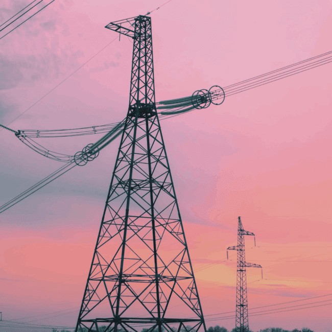 High-voltage transmission towers at sunset, representing the modernisation of grid infrastructure for renewable energy integration