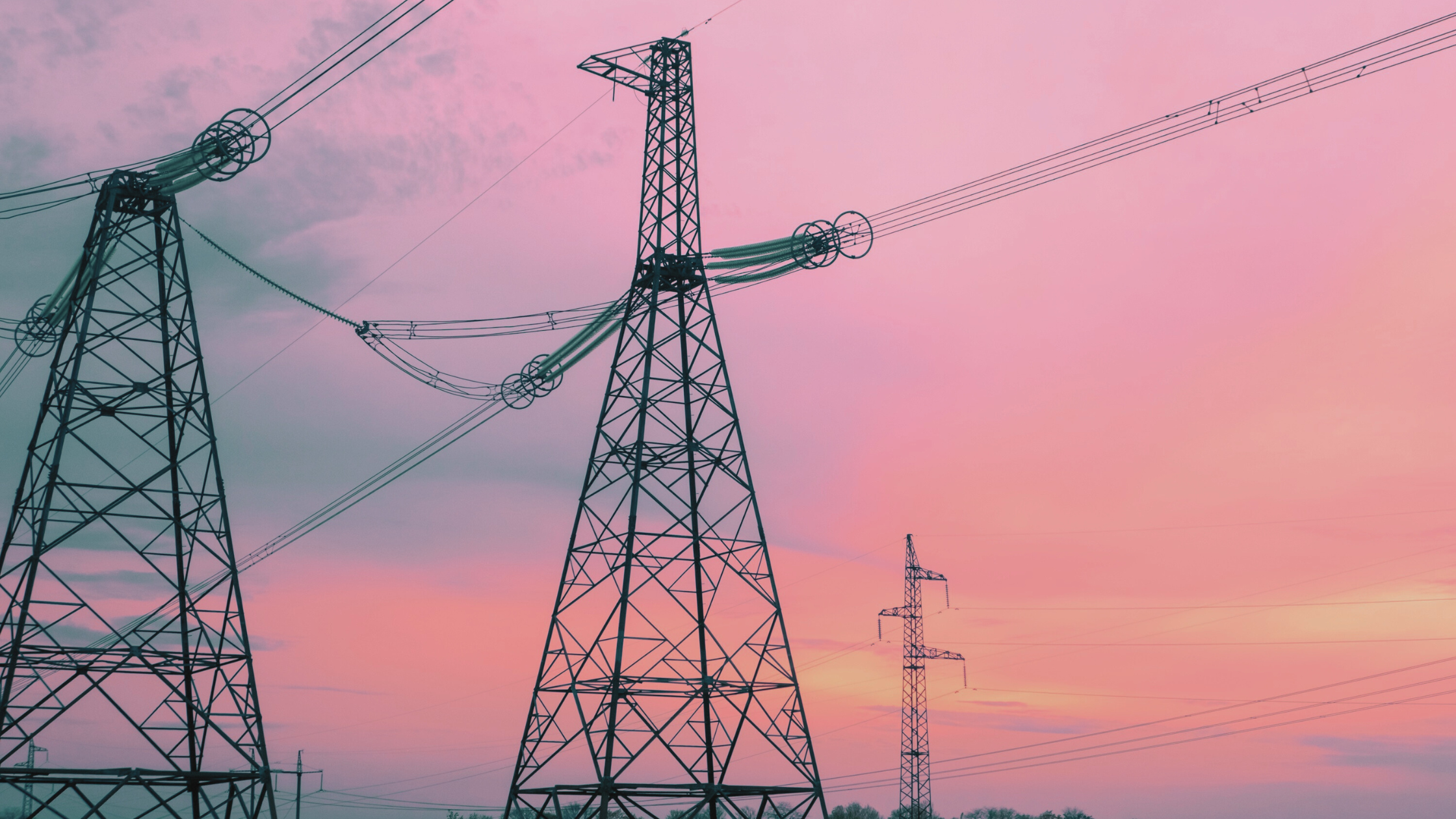 High-voltage transmission towers at sunset, representing the modernisation of grid infrastructure for renewable energy integration